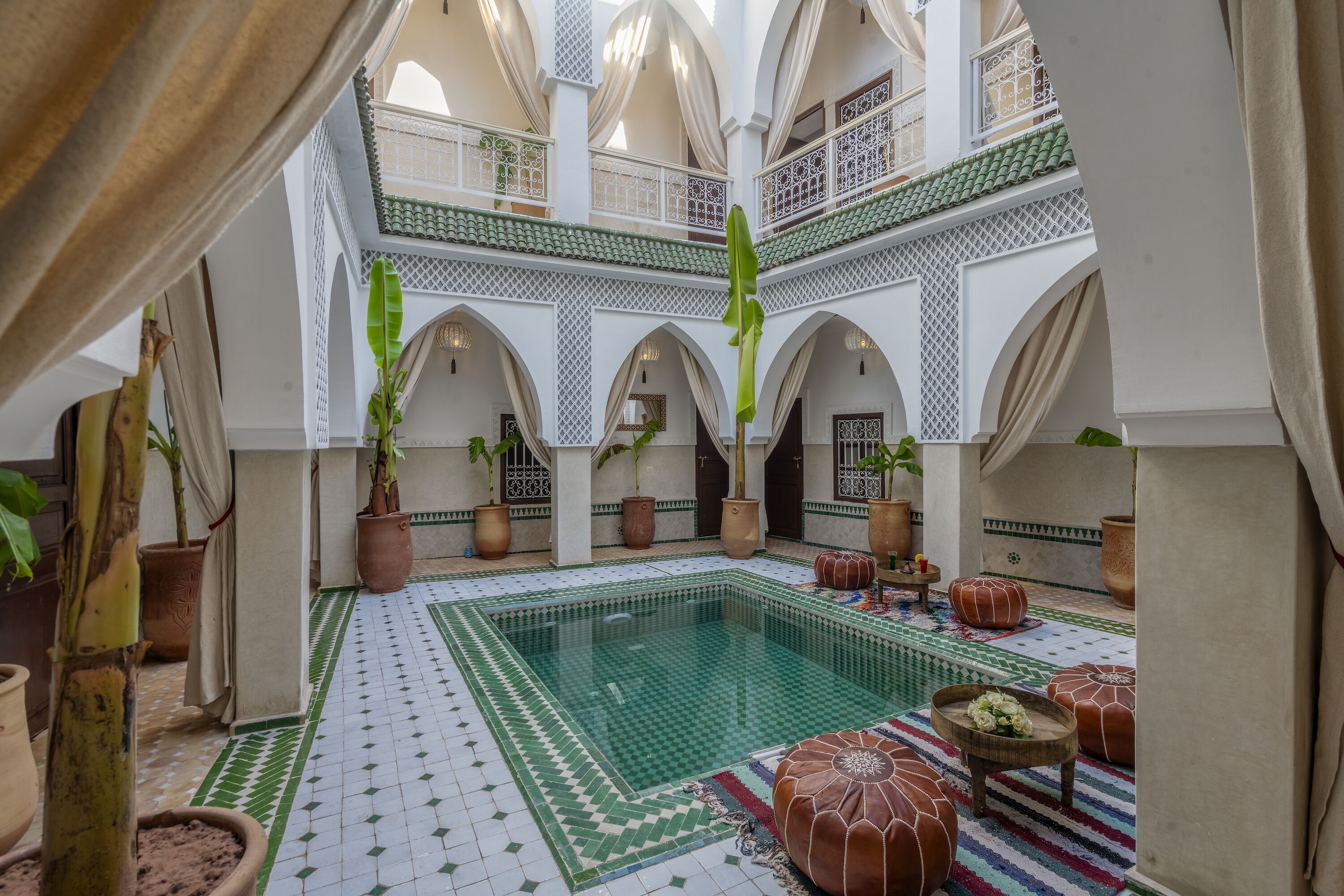 A courtyard with a pool, potted plants, and traditional Moroccan architecture.