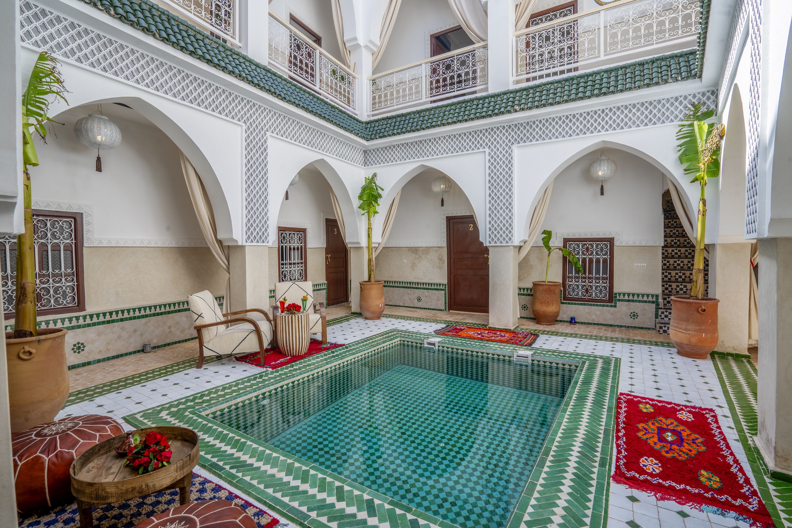 A courtyard with a swimming pool, arches, and tiled flooring.