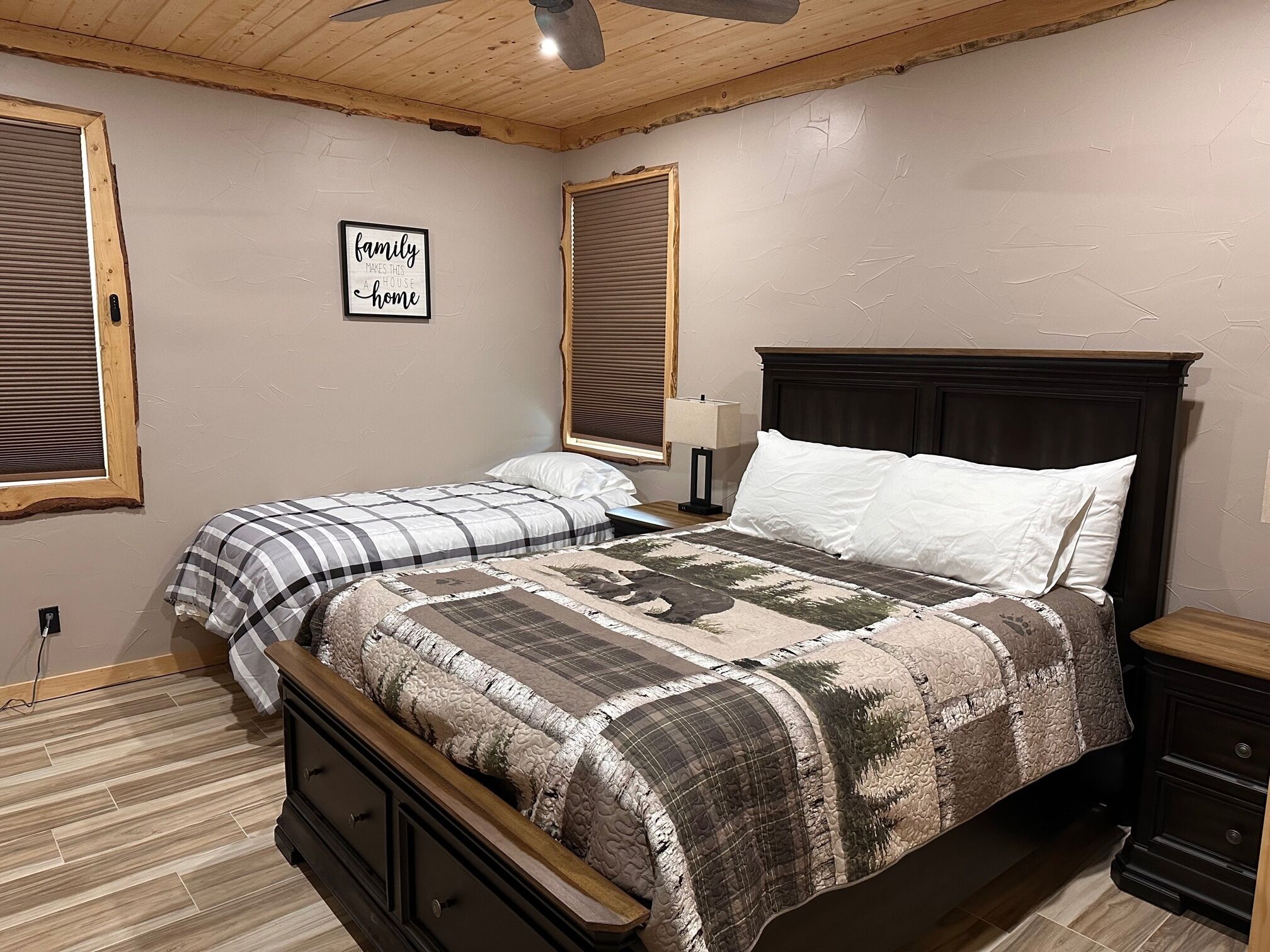 Una camera da letto con un letto, un comodino, una cassettiera e una ventola a soffitto.
