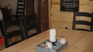Ein Holztisch mit Kerze und einer Kaffeetassen-Unterlage. An der Wand befindet sich ein 'Welcome'-Schild sowie verschiedene andere Schilder.