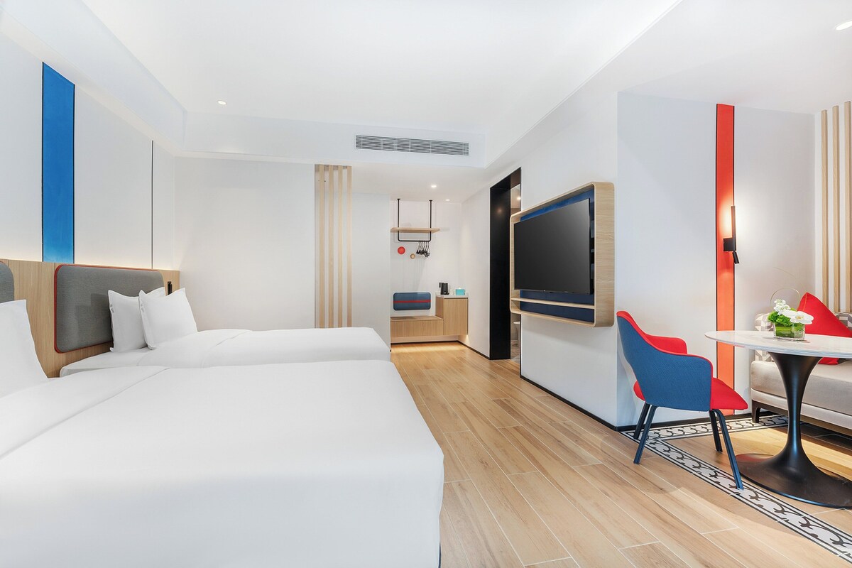 A hotel room with a bed, a desk, a chair, and a TV.