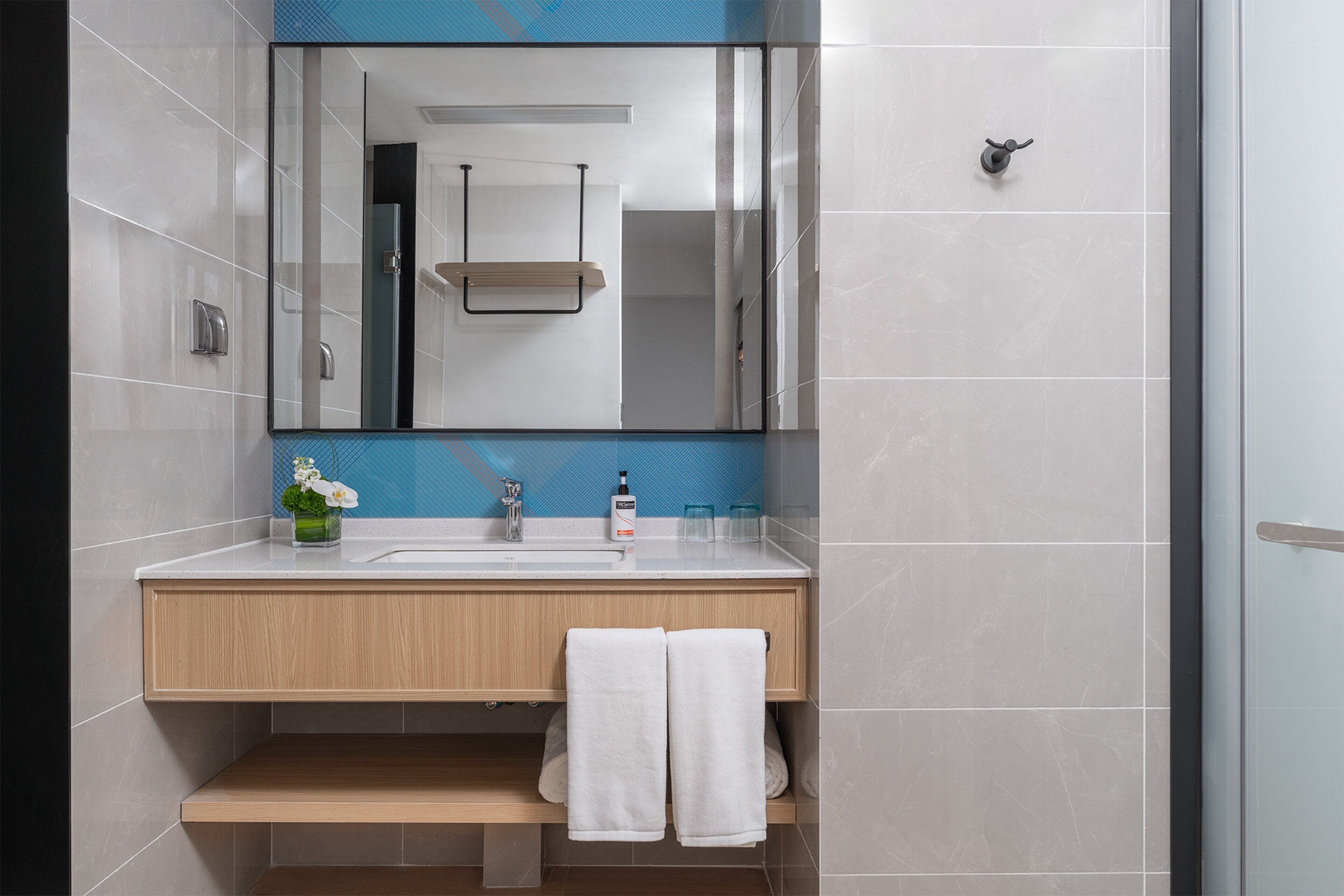 Een moderne badkamer met een grote spiegel, een wastafel en een handdoekhouder.