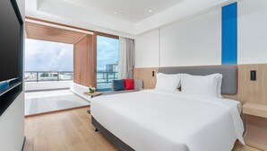 A modern hotel room with a large bed, a TV, a balcony with a city view, and a blue accent wall. - Holiday Inn Express Wenchang by IHG (Wenchang)