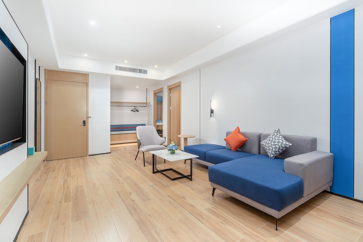 A modern living room with a blue sofa, a white coffee table, and a grey armchair.