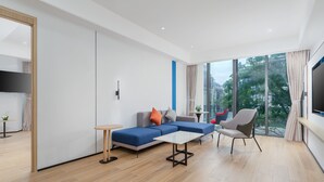 A modern living room with a sectional sofa, a coffee table, a chair, and a TV. - Holiday Inn Express Wenchang by IHG (Wenchang)