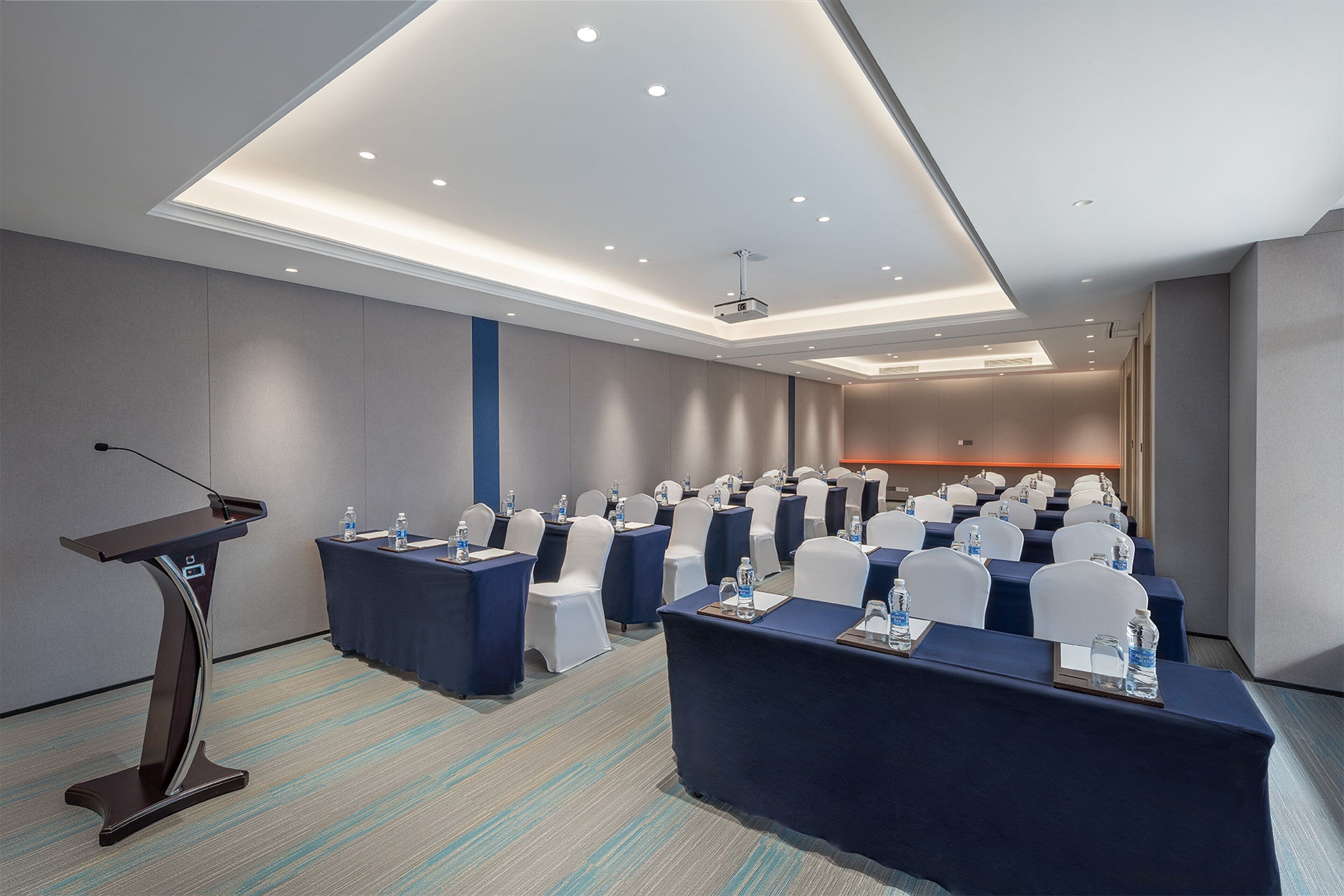 A conference room with a podium, tables, chairs, and a projector.