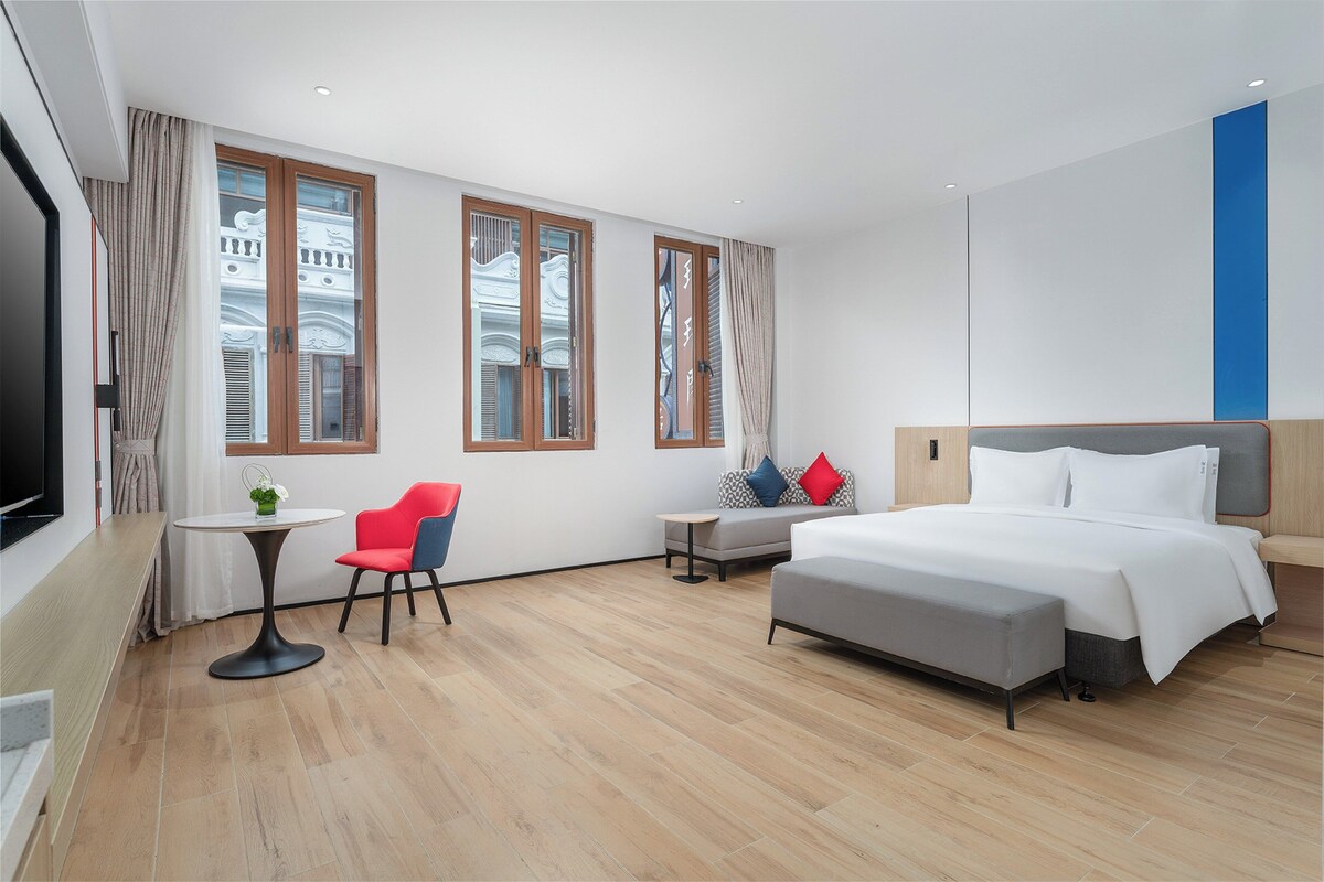 A hotel room with a bed, a desk, a chair, and a TV.