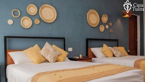 A hotel room with two beds, each with white linens and yellow accents, a blue wall with decorative plates, and a wooden headboard. - Premium House 4 BR in Downtown, Walk Everywhere! (Valladolid)