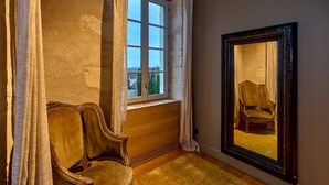 A room with a large mirror reflecting a chair, a window with curtains, and a wooden floor. - La Chapelle, the only 5-star Suite in Nevers (Nevers)