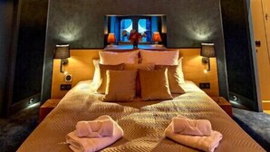 A hotel room with a large bed, a nightstand, a window with blue-tinted glass, and a starry ceiling. - La Chapelle, the only 5-star Suite in Nevers (Nevers)