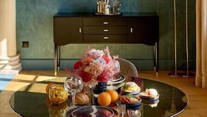 A dining table with a glass top, surrounded by various dishes and a vase of flowers. - La Chapelle, the only 5-star Suite in Nevers (Nevers)