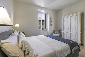 Un dormitorio con cama, armario, ventana y lámpara.