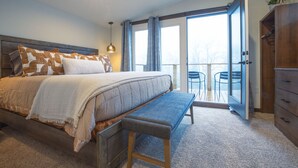 Un dormitorio con cama, banco y vistas al exterior a través de una puerta corredera.