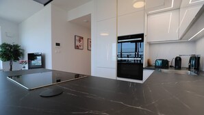 Una cocina moderna con encimera negra, horno integrado y cafetera.