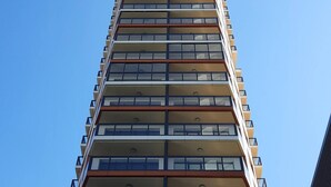 Un edificio alto y moderno con varios balcones y ventanas amplias.