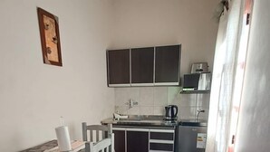 Een kleine keuken met een eethoek, een koelkast, een koffiezetapparaat en kastjes.
