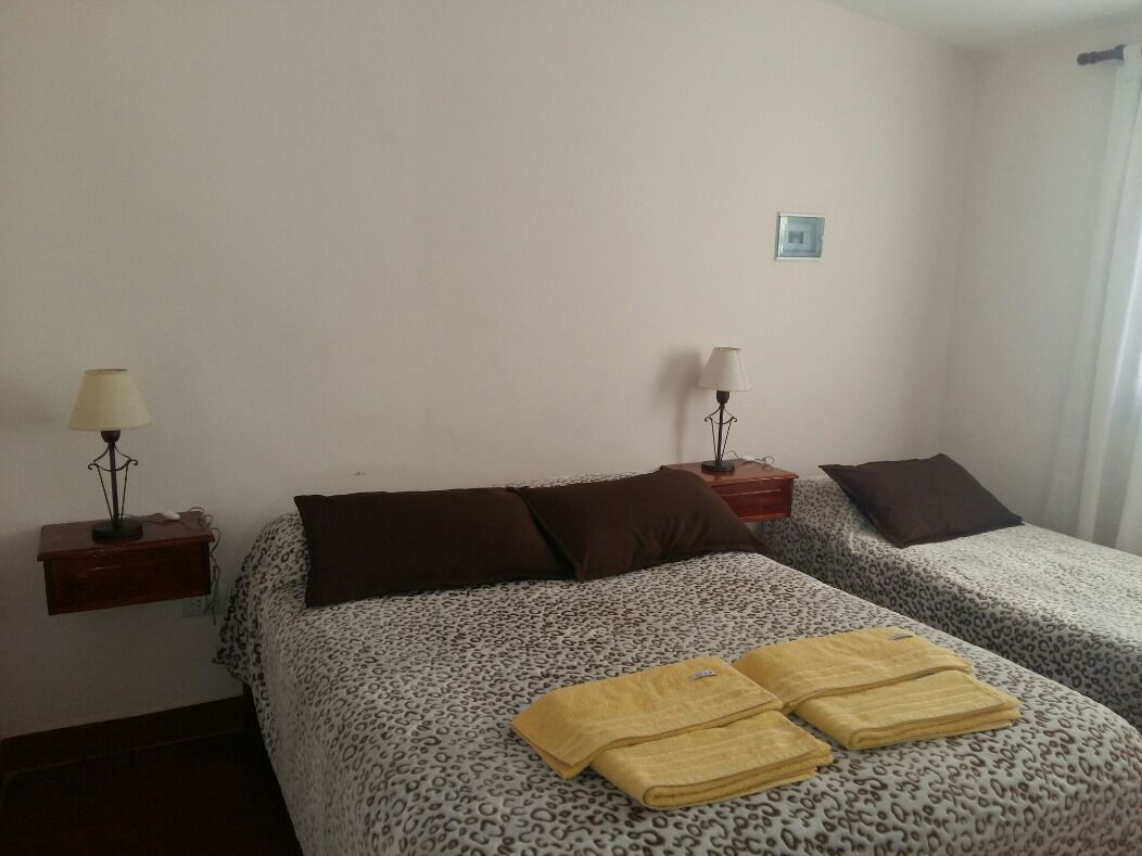 A hotel room with two beds, each with a leopard print bedspread, a small bedside table with a lamp, and a folded towel on the bed.