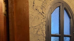 A room with a textured wall, a wooden door, and a window with frosted glass.