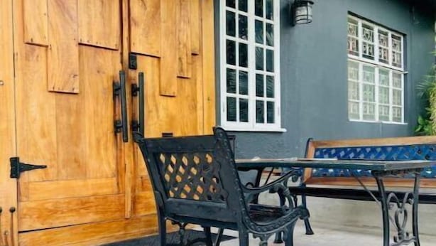 A wooden door, a table with chairs, and a window with a view of greenery.