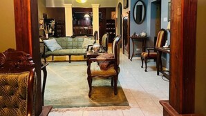 A spacious living room with a sofa, chairs, a dining table, and a chandelier.