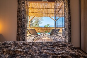 A bedroom with a view of a wooden deck and a pool.