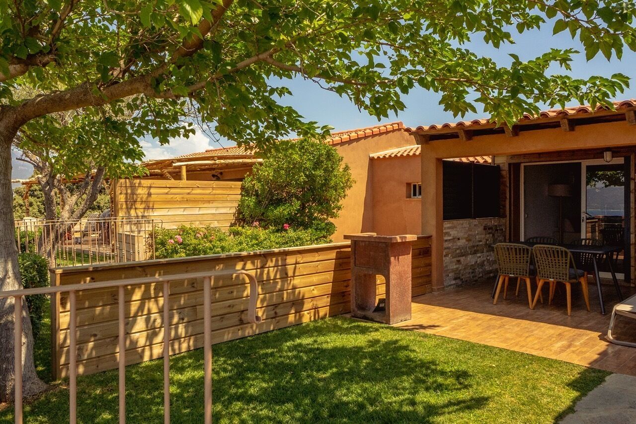 A patio with a table and chairs, a stone bench, and a wooden fence.