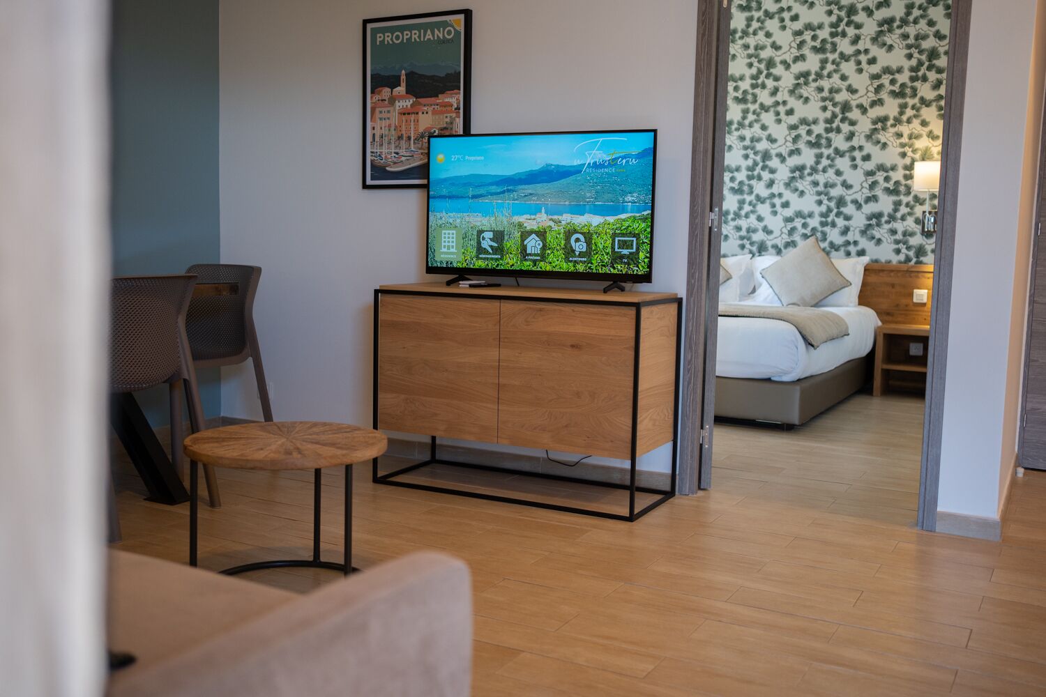 Ein modernes Wohnzimmer mit einem Holzkabinett, einem Fernseher und einem Essbereich mit Stühlen.