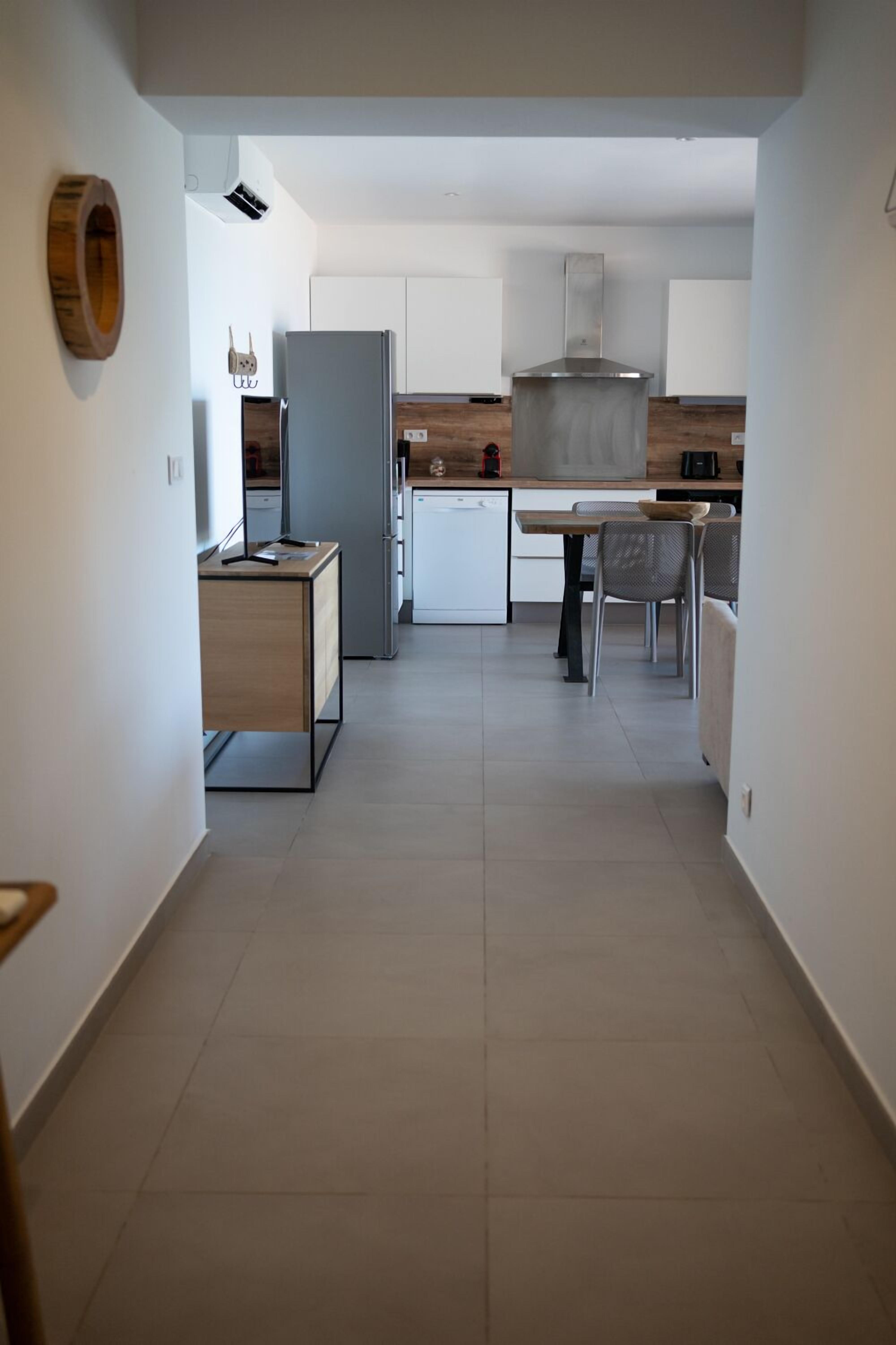 Une cuisine moderne dotée d’un îlot central, de meubles blancs et d’un coin repas avec des chaises.