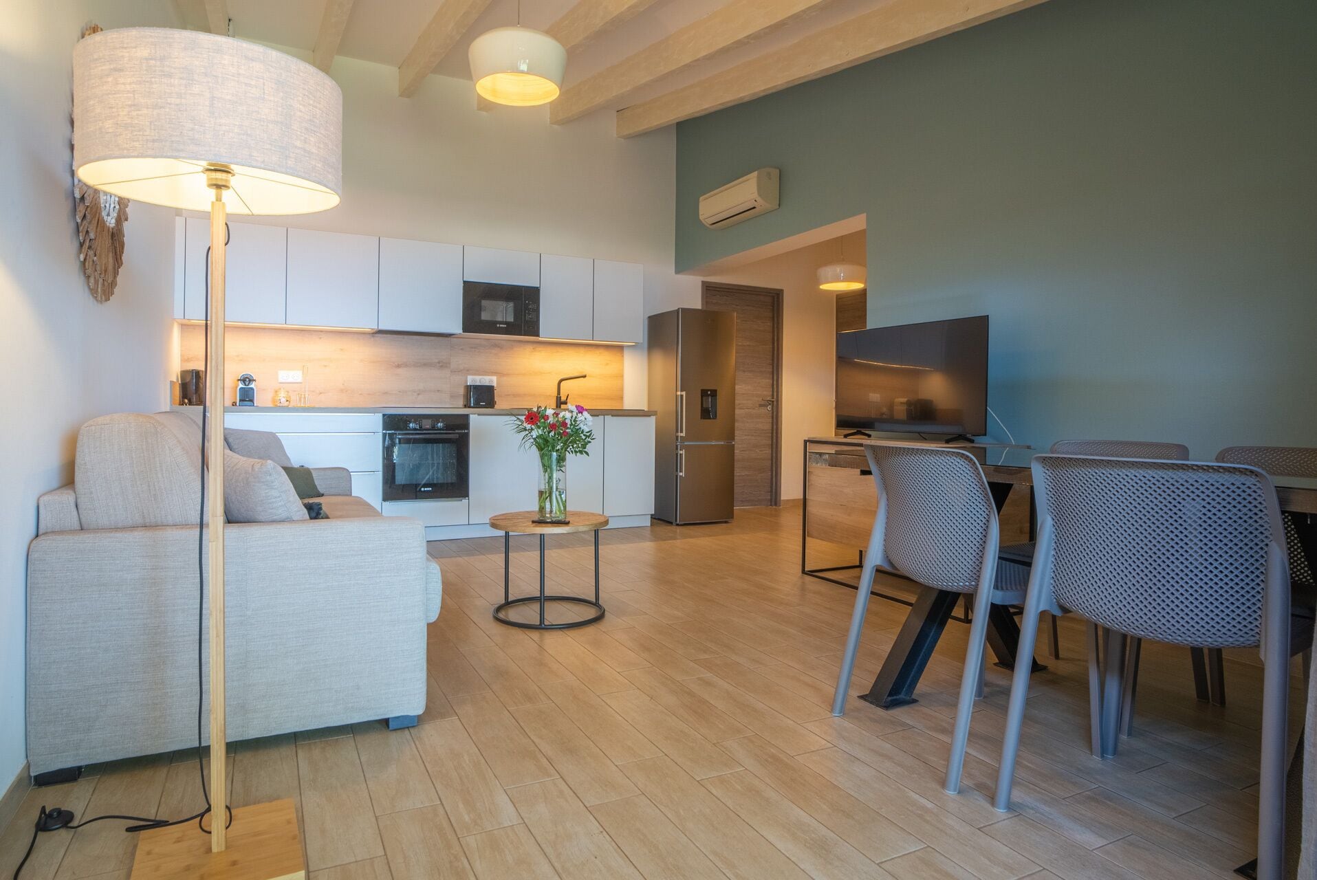 Un espace de vie moderne comprenant un canapé, une table à manger, des chaises, un coin cuisine et un grand lampadaire.