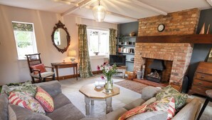 A cozy living room with a fireplace, comfortable seating, and a bookshelf. - The Waggon Shed (Nottingham)