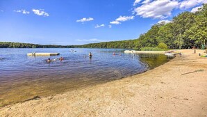 A beach with clear water, people swimming, and a forested area in the background. - Riverfront FirePit! HotTub-Pool-Beaches-Gameroom (Gouldsboro)