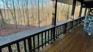 A wooden deck with a railing, overlooking a forested area. - Quaint cottage with a beautiful view. (Greenville)