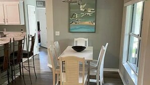 Un comedor con una mesa y sillas, un cuadro en la pared y una ventana con vistas.