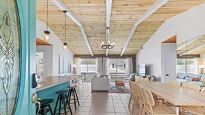 A spacious kitchen with a wooden ceiling, a bar area with stools, and a dining area with a long table and chairs. - New! Big Discounts!! Nights of Lights, Beach, Cowboy Pool, Bike, Grills, Pets (St. Augustine)