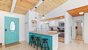A modern kitchen with a central island, wooden ceiling, and bar stools. - New! Big Discounts!! Nights of Lights, Beach, Cowboy Pool, Bike, Grills, Pets (St. Augustine)