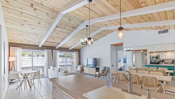 A spacious kitchen with a large island, white cabinetry, and a dining area with wicker chairs. - New! Big Discounts!! Nights of Lights, Beach, Cowboy Pool, Bike, Grills, Pets (St. Augustine)