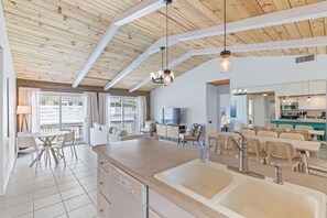 A spacious kitchen with a large island, white cabinetry, and a dining area with wicker chairs. - New! Big Discounts!! Nights of Lights, Beach, Cowboy Pool, Bike, Grills, Pets (St. Augustine)