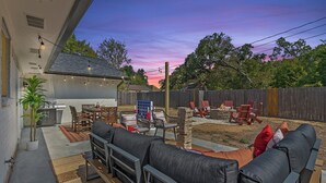 An outdoor patio area with a dining table, chairs, and a cushioned seating area. - The Howdy Retreat - Gameday Bus - Near Texas A&M (College Station)