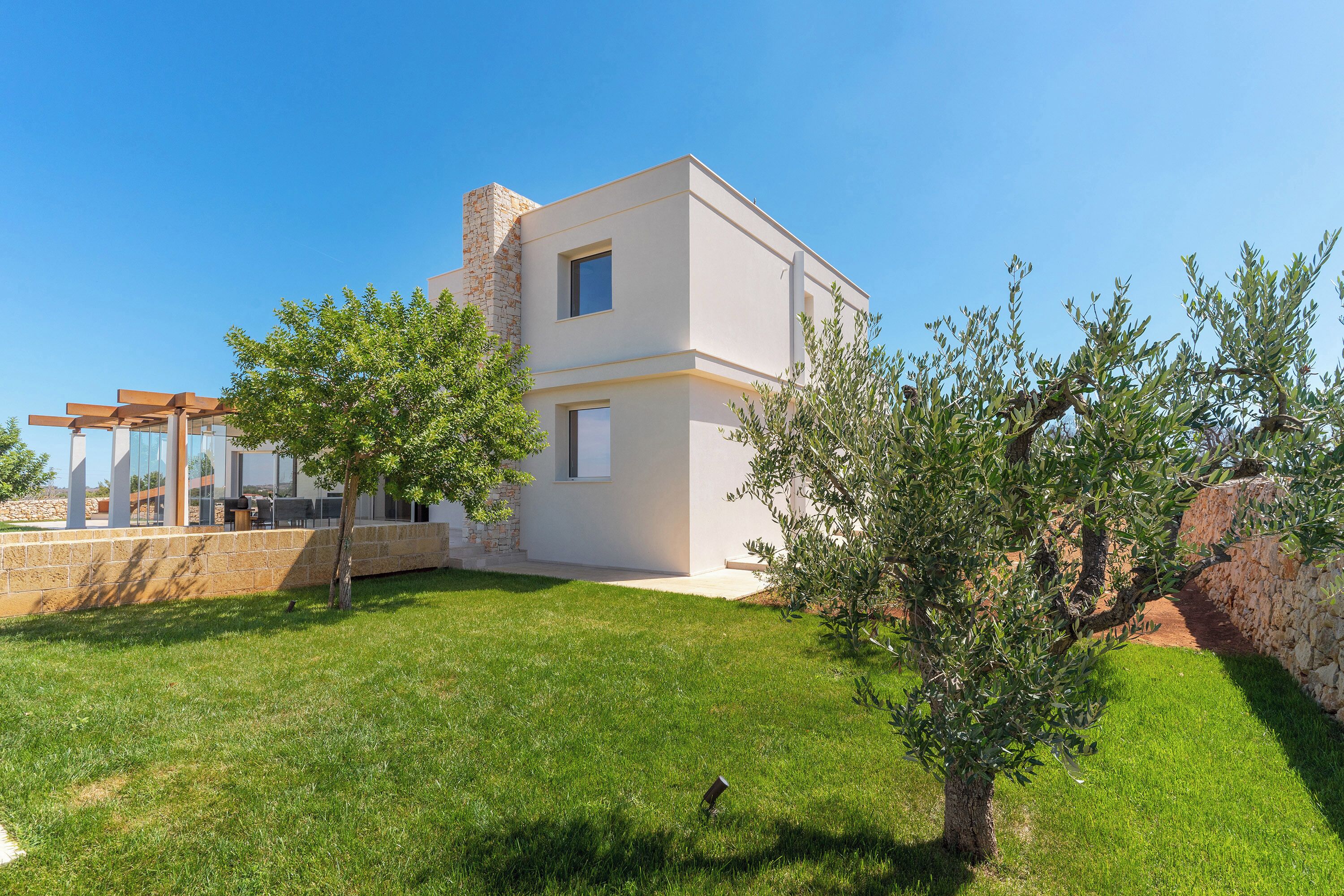 A modern house with a flat roof, a stone chimney, and a well-maintained lawn.