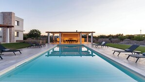 A modern pool area with lounge chairs and a covered seating area. - 3239 Domina 55 by Perle di Puglia (Casarano)