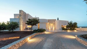 A modern house with a stone facade, a gravel driveway, and outdoor seating. - 3239 Domina 55 by Perle di Puglia (Casarano)