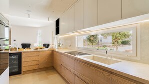 A modern kitchen with wooden cabinets, a built-in dishwasher, and a window overlooking a garden. - 3239 Domina 55 by Perle di Puglia (Casarano)