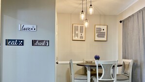 A dining area with a table and chairs, framed artwork on the wall, and decorative signs saying "love," "eat," and "drink." - Modern Townhome w/ Balcony • Walk to FUSE Stadium (Gastonia)