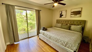 A bedroom with a bed, a ceiling fan, and a view through a sliding glass door. - Modern Townhome w/ Balcony • Walk to FUSE Stadium (Gastonia)