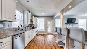 A modern kitchen with white cabinets, a granite countertop, and a wooden floor. - 6 Bedroom Home with Pool, Centrally Located (The Colony)