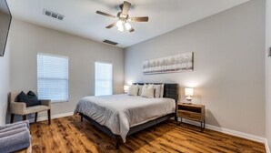 A bedroom with a bed, a chair, a nightstand, a ceiling fan, and a window with blinds. - 6 Bedroom Home with Pool, Centrally Located (The Colony)