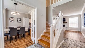 A modern interior with a dining area, kitchen, and staircase. - 6 Bedroom Home with Pool, Centrally Located (The Colony)