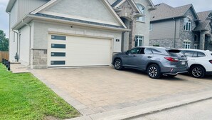 Ein modernes, zweistöckiges Haus mit Garage, zwei Autos davor und einem gepflegten Rasen.