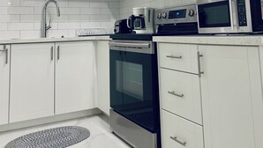 Eine moderne Küche mit weißen Schränken, Edelstahlgeräten und einem schwarzen Backofen.