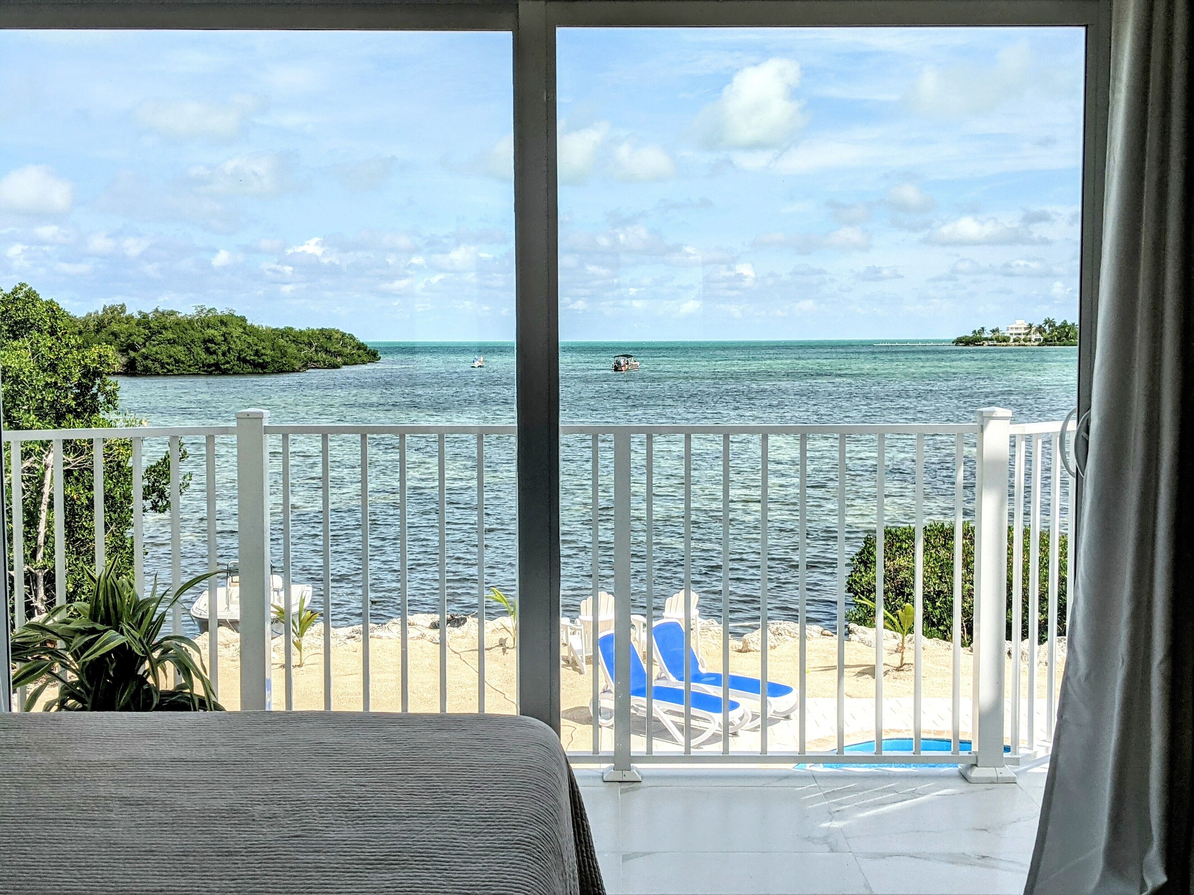 Un balcon avec vue sur la mer, une piscine et des chaises longues sur la plage.
